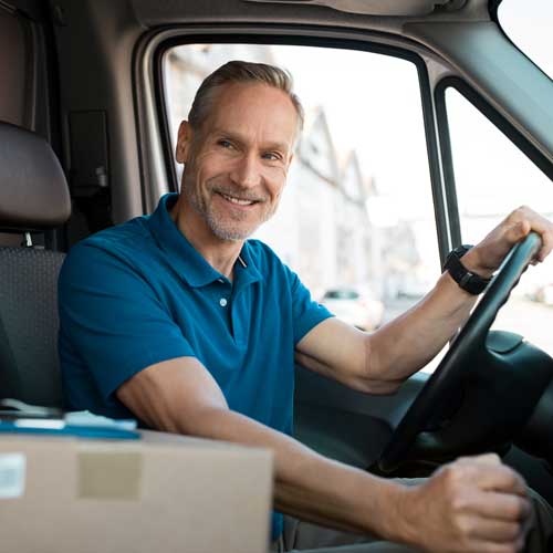 Man in a van smiling with a parcel next to him